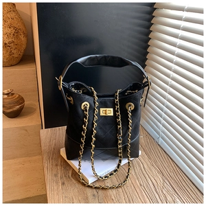 Detail of black quilted bucket bag featuring matte leather texture and gold chain strap
