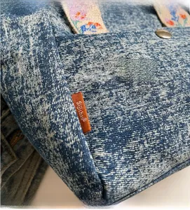 Detailed macro view of denim fabric texture with floral embroidery webbing handle