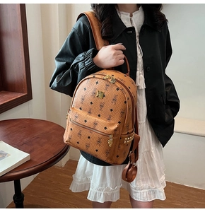 Detail view of cognac brown leather backpack with rabbit patterns and gold metal studs