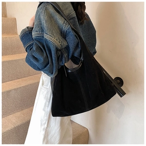 Détail du grand sac cabas noir en daim avec surpiqûres élégantes porté par un mannequin