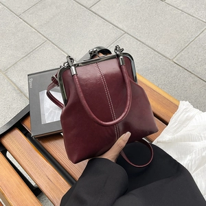 Close-up of retro burgundy shell-shaped handbag with white contrast stitching detail