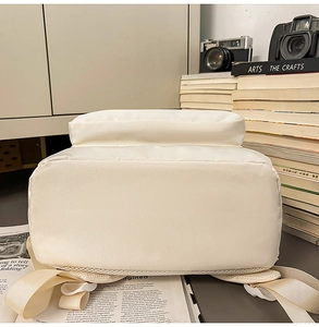 Detailed base of cream canvas backpack with books and vintage camera aesthetic