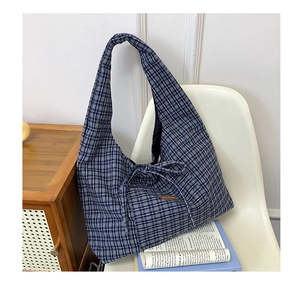 Detail of blue and white checkered tote bag featuring a decorative bow tie closure