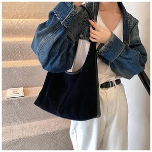 Détail du grand sac hobo en daim noir avec bandoulière large porté par un mannequin