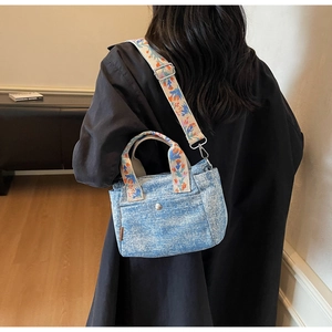 Detailed view of blue denim tote bag with colorful ethnic floral embroidery strap