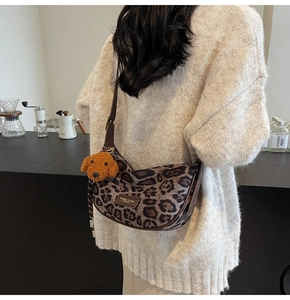 Leopard print crescent bag with brown leather strap and cute plush dog charm detail