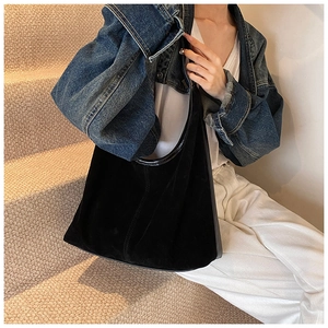 Détail de la texture et des coutures du sac hobo en daim noir sur un modèle