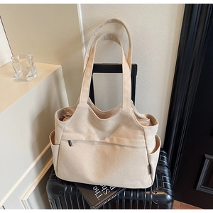 Dettaglio della borsa tote in tela color crema sulla valigia con trama e tasca laterale