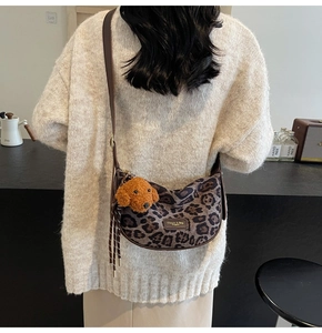 Macro shot of leopard print shoulder bag with brown leather logo and cute teddy charm