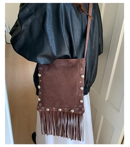 Detail of bohemian brown suede crossbody bag with vintage tassels and silver rivets
