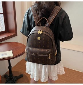 Rear view of a stylish brown monogrammed backpack worn by a model in a cozy interior