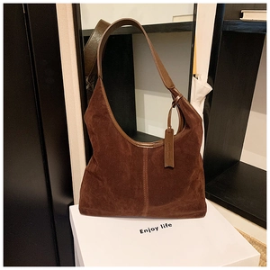 Détail du sac hobo en daim marron foncé avec bandoulière en cuir et étiquette embossée