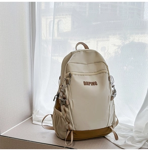 Detail of cream backpack with DAPING logo, buckles, and side water bottle pocket
