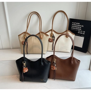 Detail view of four large tote bags in black, brown, and cream with bear charms