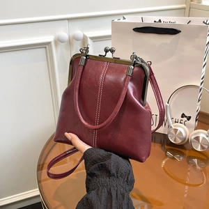 Detail view of wine red vintage shell bag with double white stitching and metal clasp
