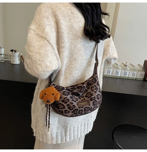 Detail of leopard print crossbody bag with leather trim and brown teddy bear charm
