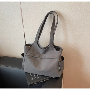 Vista dettagliata della borsa tote in tela grigia con tasca laterale e logo laterale