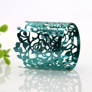 Macro detail of teal metallic napkin ring with intricate laser-cut rose floral pattern