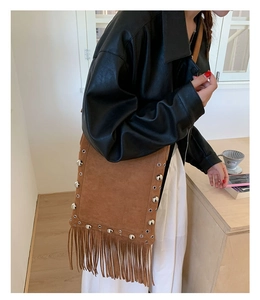 Close-up of brown suede tassel bag with silver studs and bohemian fringe detail