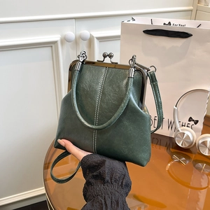 Detail of dark green vintage shell bag with contrast stitching and metal clasp
