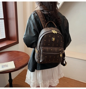 Detail of a brown leather backpack with cartoon rabbit pattern and gold metal hardware
