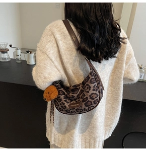 Detailed back view of leopard print crescent bag with brown bear charm on shoulder