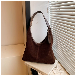 Vue macro du sac hobo en daim marron foncé avec bandoulière en cuir et étiquette