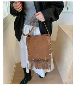 Detail of brown suede crossbody bag with silver studs and long bohemian tassels
