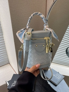 Light blue bucket bag with woven texture, silk scarf handle, and gold padlock hardware
