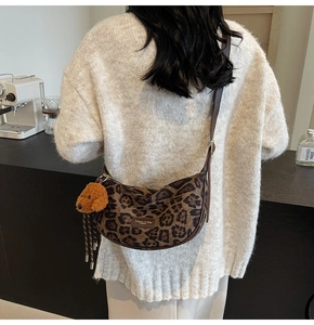 Detail of leopard print crescent bag with cute bear charm and adjustable leather strap