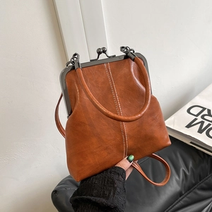 Detail of vintage brown shell-shaped crossbody bag with metal clasp and textured leather finish