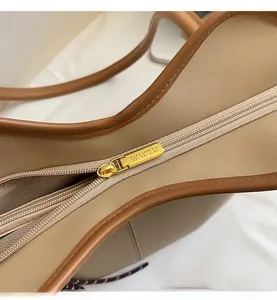 Close-up of golden metal zipper with logo on a light brown leather tote bag