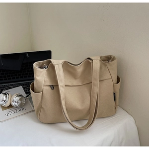 Dettaglio delle tasche laterali e delle cuciture della borsa tote in tela resistente beige