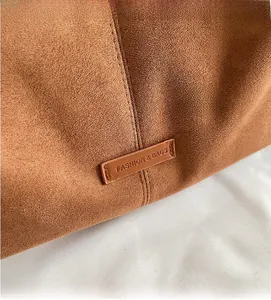Dettaglio della borsa tote in pelle scamosciata con etichetta Fashion & Bags