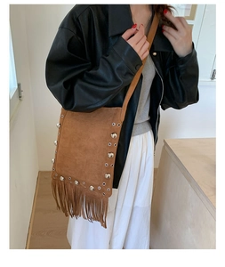 Detail of brown suede crossbody bag with decorative tassels and silver metallic rivets