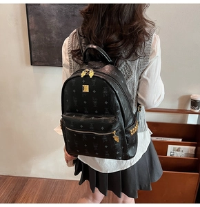 Detail of black pebbled leather backpack featuring vintage monogram and golden rivets