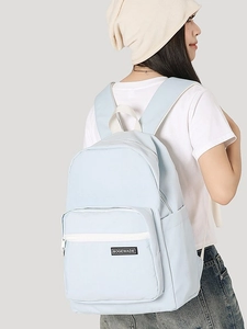 Minimalist light blue large capacity backpack for students shown on model against grey background