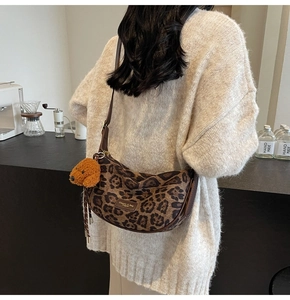 Leopard print crescent bag detail with cute dog plush charm and brown zip strap