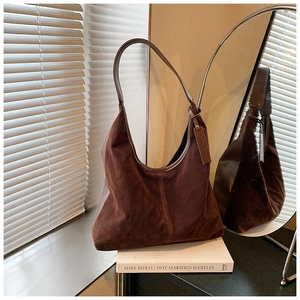 Détail du sac hobo en daim marron avec large bandoulière et coutures verticales
