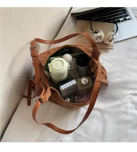 Vista dall'alto di una capiente borsa hobo in pelle scamosciata marrone con oggetti quotidiani