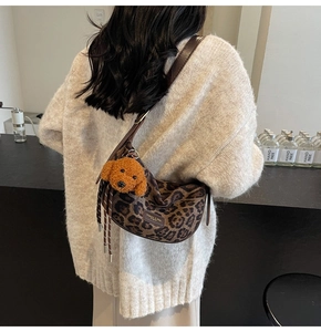 Detail of leopard print crossbody bag with cute teddy dog plush charm and leather strap