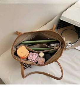 Detailed interior of a brown leather tote bag showing multi-layer compartments for storage