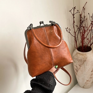 Detail of vintage shell-shaped crossbody bag with polished brown PU leather and metal frame