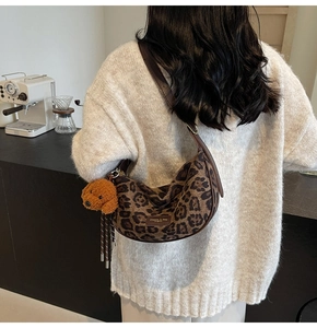 Detailed back view of leopard print crescent bag with leather strap and plush dog charm