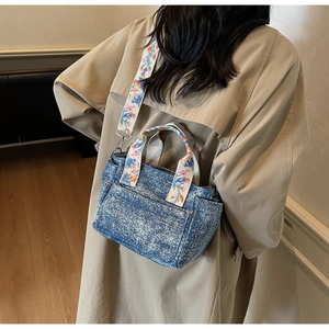Detail of blue denim tote bag with colorful floral embroidery on the shoulder strap