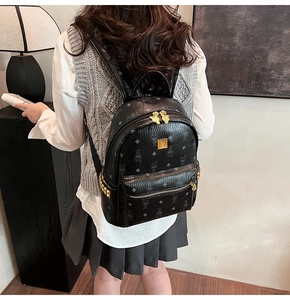 Detail of black backpack with gold rivets and rabbit monogram pattern on side view