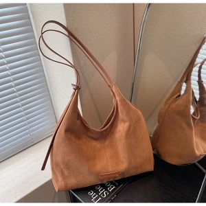 Dettaglio di borsa hobo in camoscio marrone con tracolla regolabile e logo goffrato