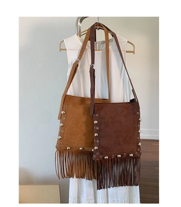 Detail of bohemian suede crossbody bags with silver metal studs and long fringe tassels