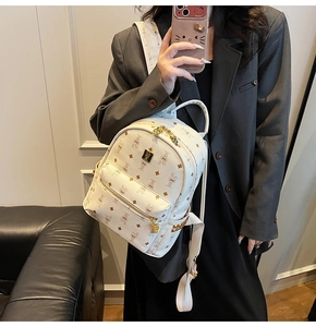 Detailed shot of white mini backpack with brown rabbit pattern and gold metal hardware