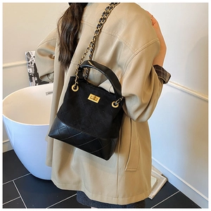 Close-up of black quilted velvet bucket bag with gold chain strap and turn-lock